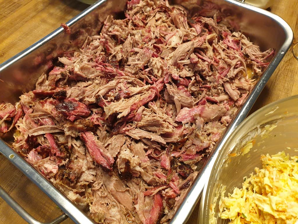 Pulled pork effiloché dans un plat — smoke ring, bark et jus